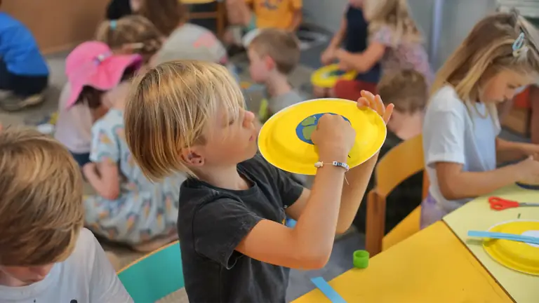 A child making a paper-plate project at Alma Forest School